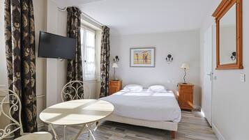 Un dormitorio con cama, televisor, mesa y silla.
