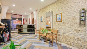 Un vestíbulo de hotel con pared de piedra, mobiliario de madera y suelo con patrón de espiga.