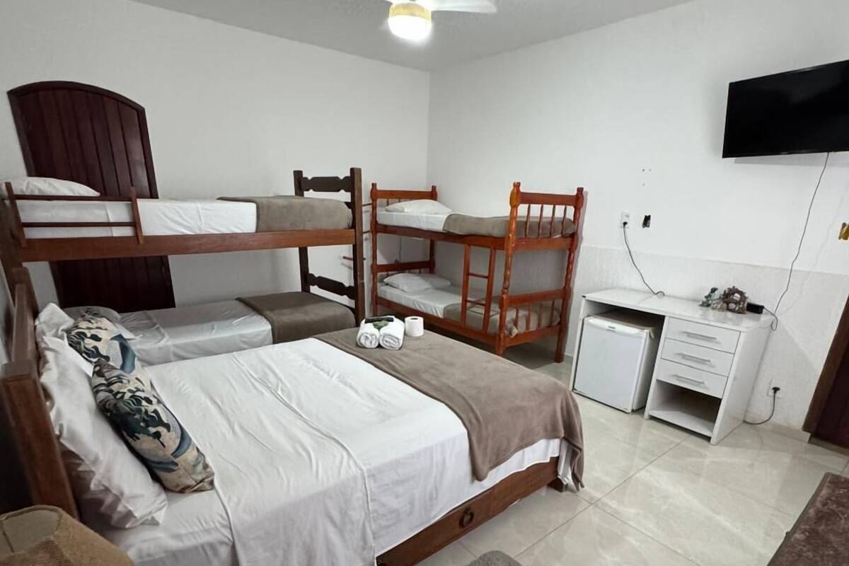 Un dormitorio con literas, un escritorio, una silla, un televisor y un refrigerador pequeño.