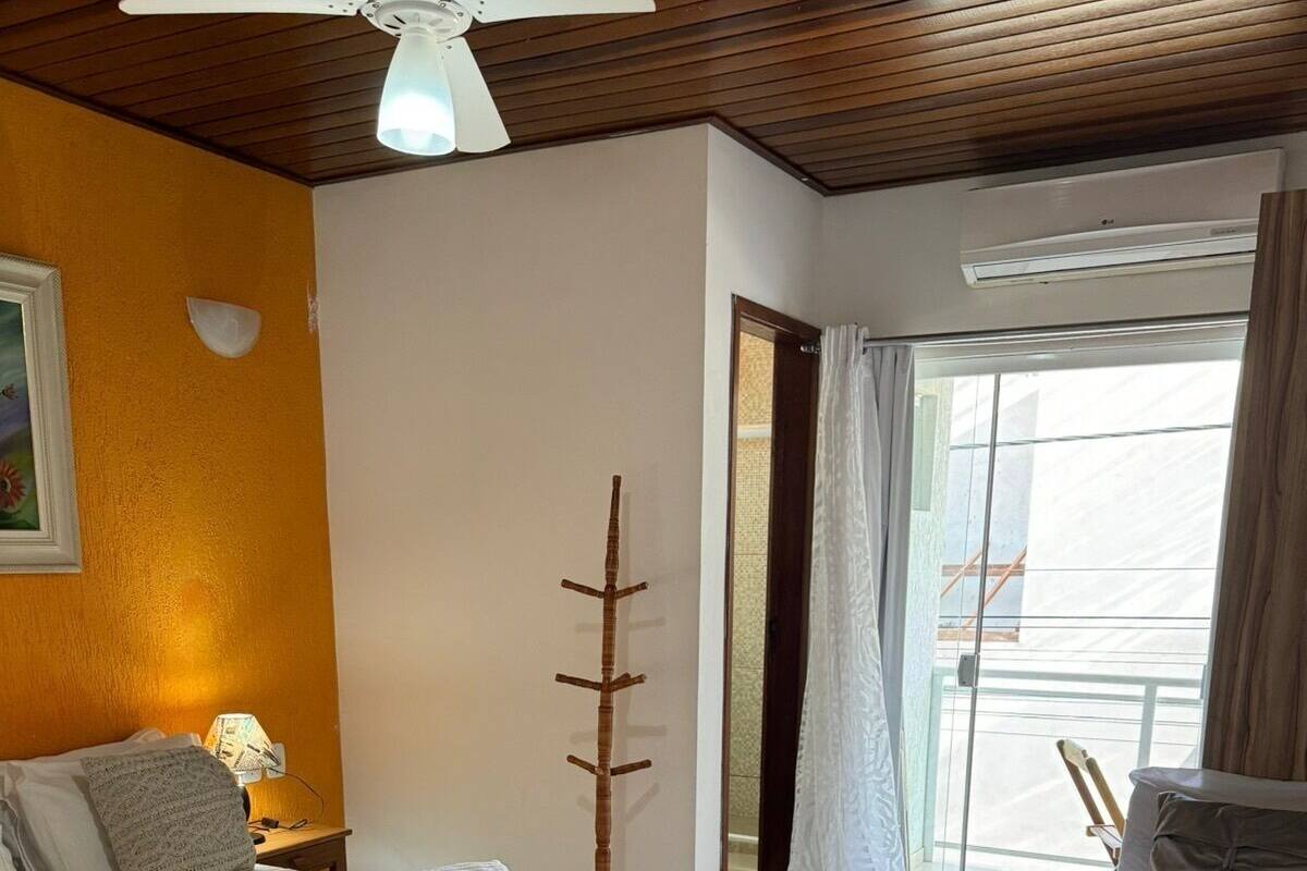 Habitación de hotel con dos camas, ventilador de techo, unidad de aire acondicionado y vista a través de un ventanal.