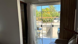 A hotel room with a balcony, a bed, a sofa, and a small table with a plant. - Pousada Sereia de Geriba (Búzios)