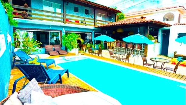 A poolside area with lounge chairs, umbrellas, and a small table. - Pousada Sereia de Geriba (Búzios)