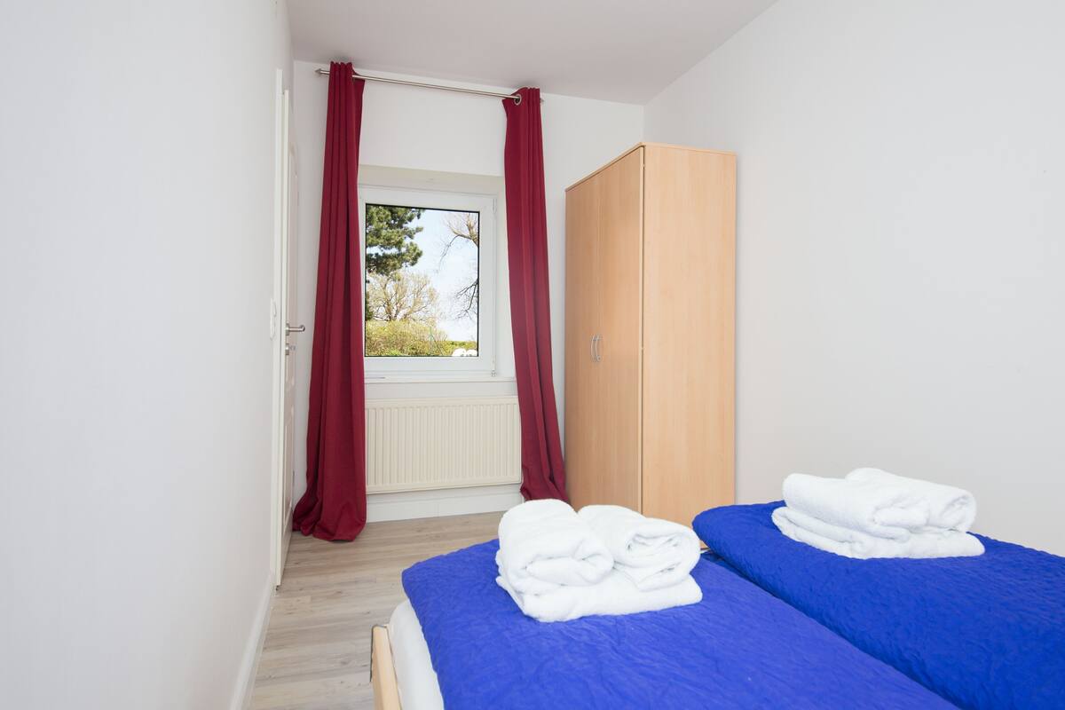 Un dormitorio con dos camas, un armario y una ventana con cortinas.