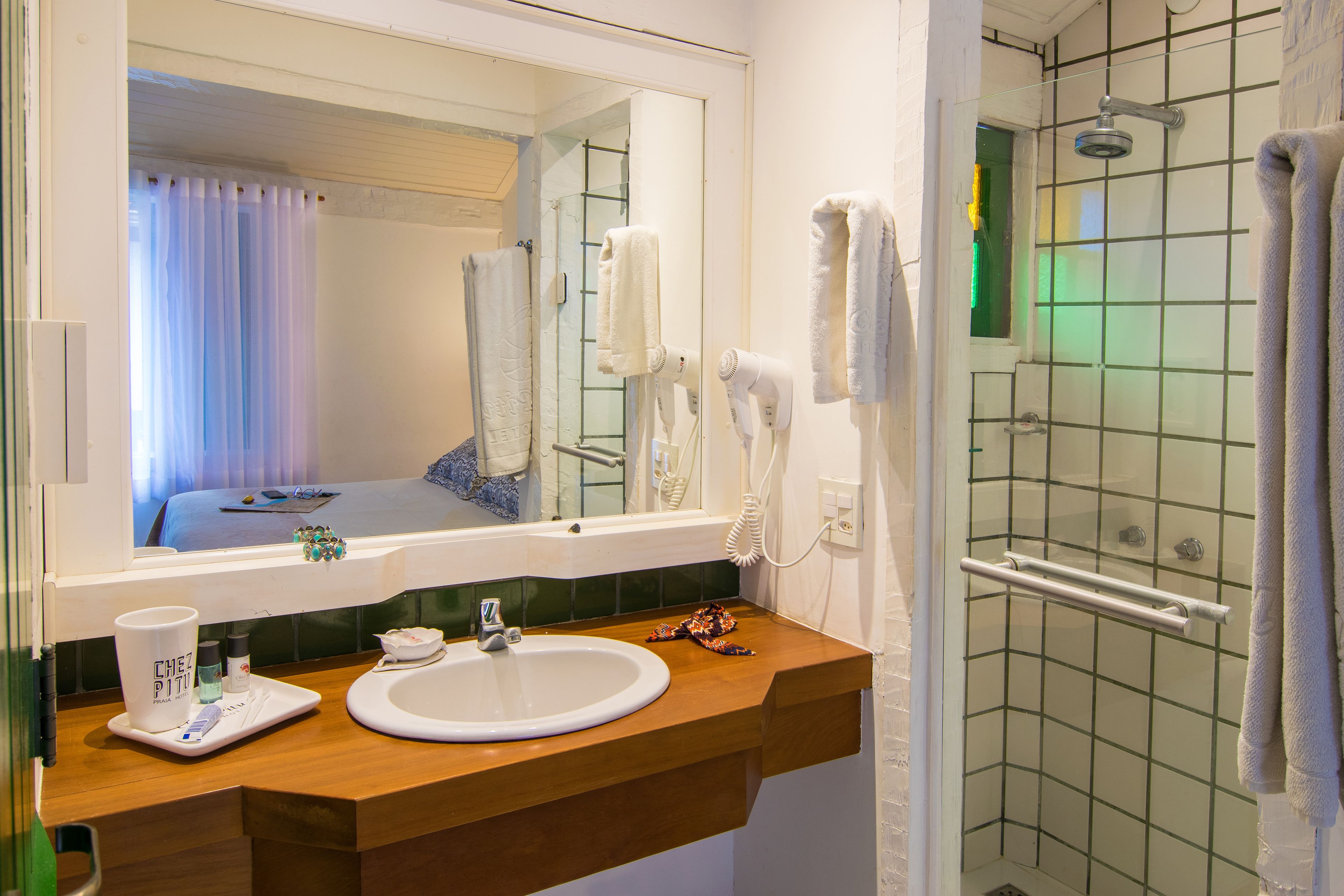 Une salle de bain avec un meuble-lavabo en bois, un lavabo blanc, un miroir et une douche dotée d’une porte en verre.