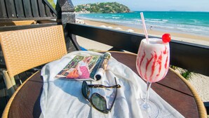 A beachside table with a drink, sunglasses, and a magazine. - Chez Pitu Praia Hotel (Búzios)