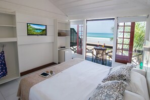 Un dormitorio con cama, televisión, escritorio y vista a la playa.