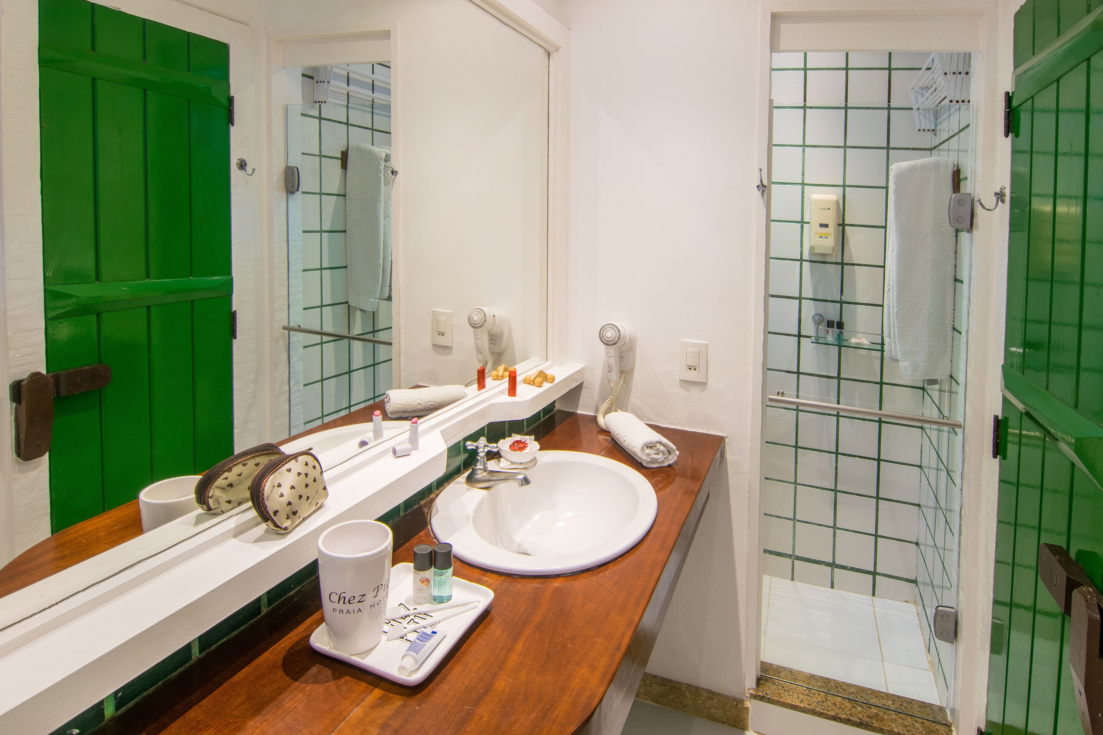 A bathroom with a green door, white tiles, a sink, and a mirror.