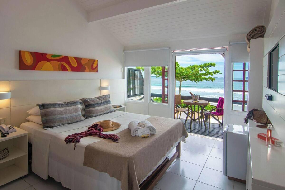 A hotel room with a bed, bedside table, and a view of the ocean.