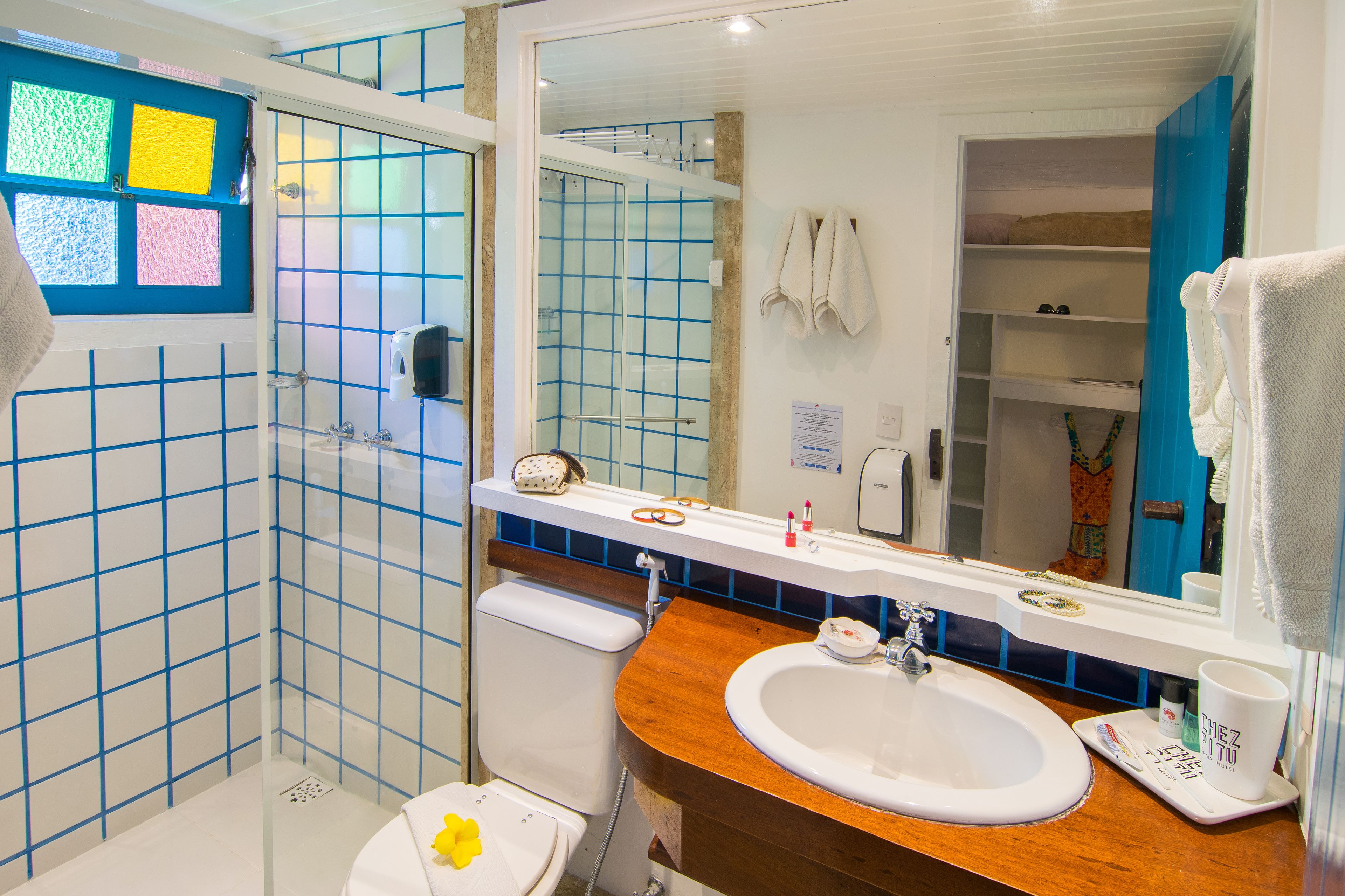 A bathroom with a white sink, a mirror, and a shower with blue tiles.