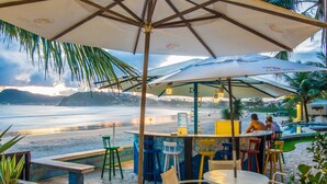 A beachside bar with outdoor seating, umbrellas, and a view of the ocean. - Chez Pitu Praia Hotel (Búzios)