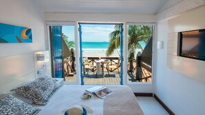 A bedroom with a bed, a TV, and a view of the beach. - Chez Pitu Praia Hotel (Búzios)