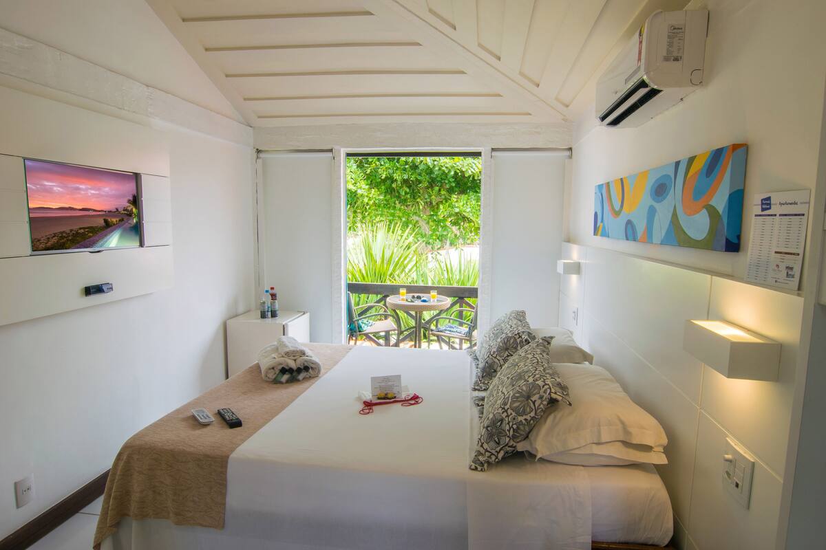 Une chambre d’hôtel avec un lit, une télévision, un tableau et une vue sur la verdure environnante.