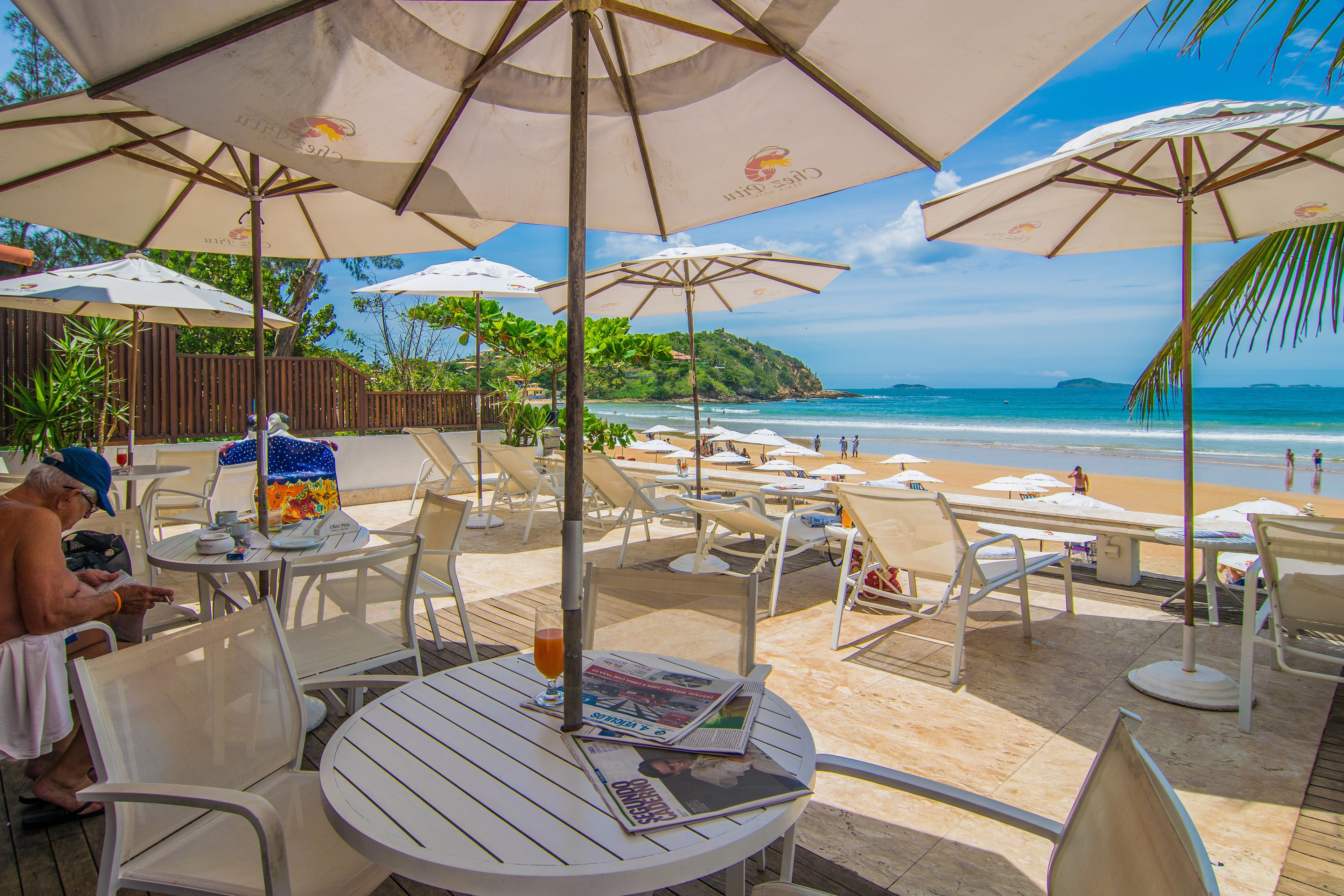 A beachside café with outdoor seating, umbrellas, and a view of the ocean.
