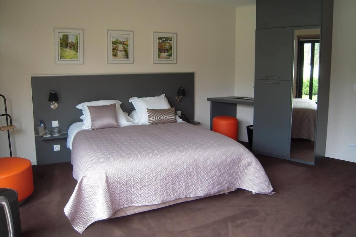 A bedroom with a bed, bedside tables, a desk, and a chair.