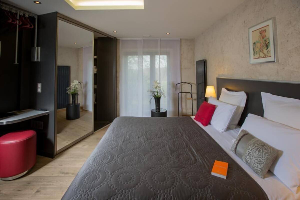 A modern hotel room with a large bed, a desk, and a mirror.