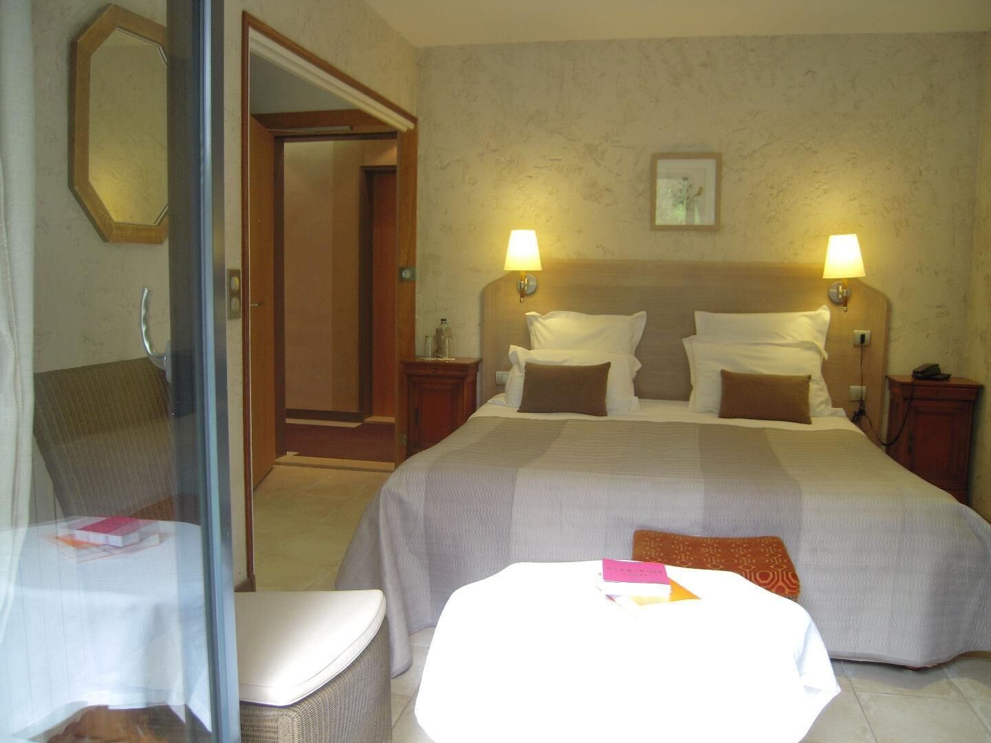 Une chambre d’hôtel avec un grand lit, deux lampes de chevet, une table de chevet, une chaise et une petite table sur laquelle se trouve un livre.