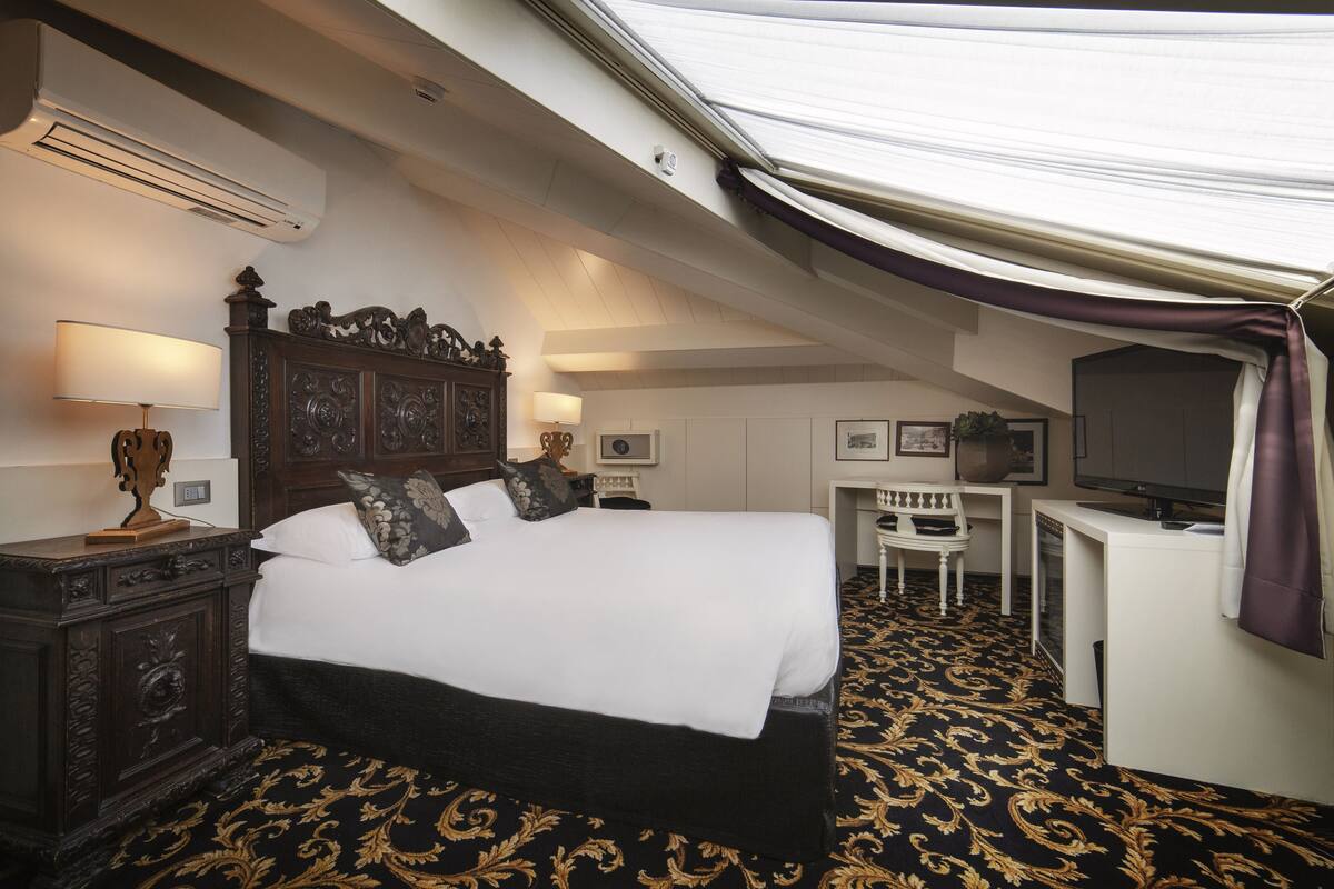 Una habitación de hotel con una cama grande, un escritorio, un televisor y un aire acondicionado.