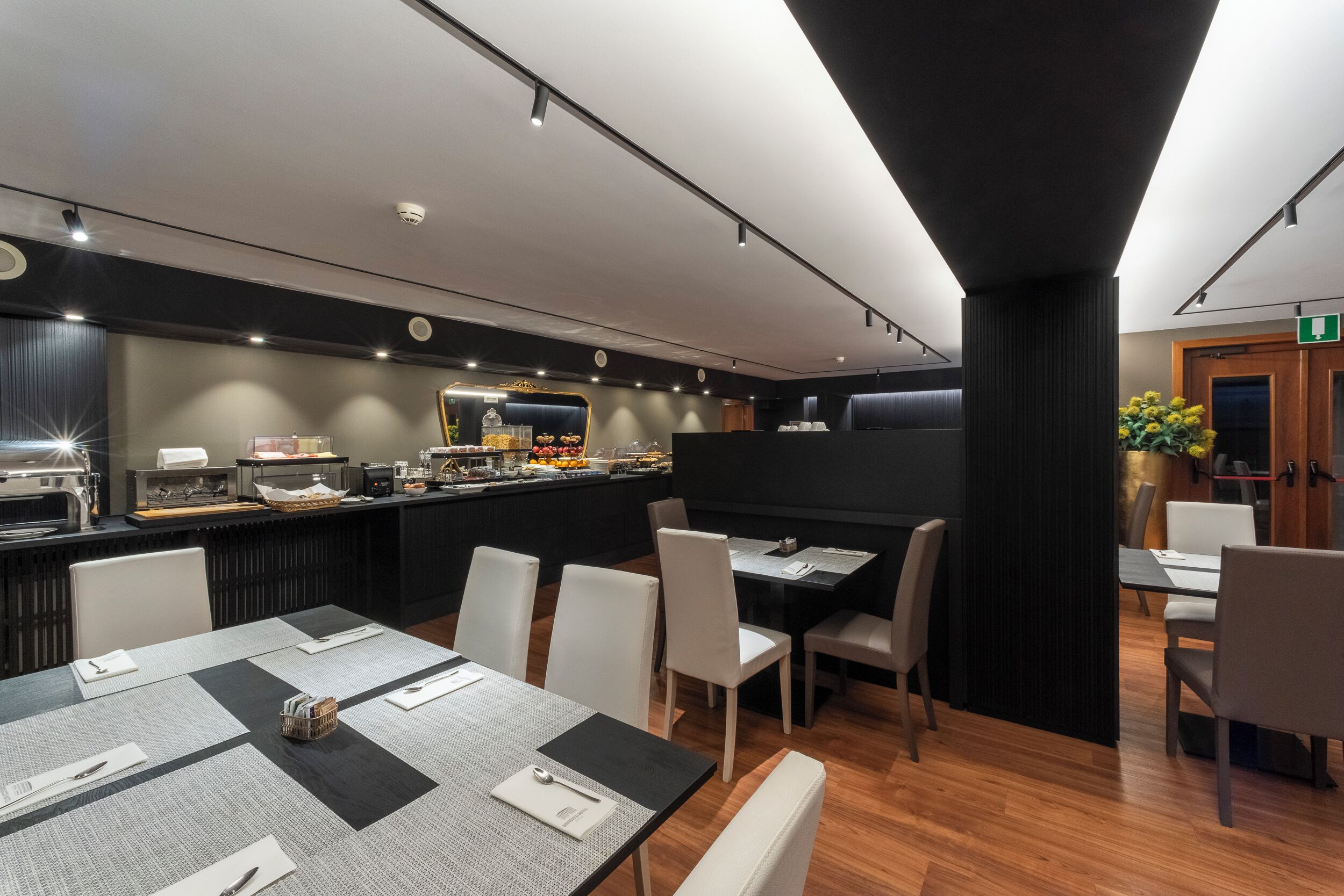 Ein modernes Restaurant mit einer langen Theke, weißen Stühlen und einer schwarzen Trennwand.