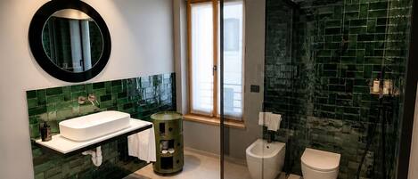 A modern bathroom with a glass-enclosed shower, a white sink, and a bidet.