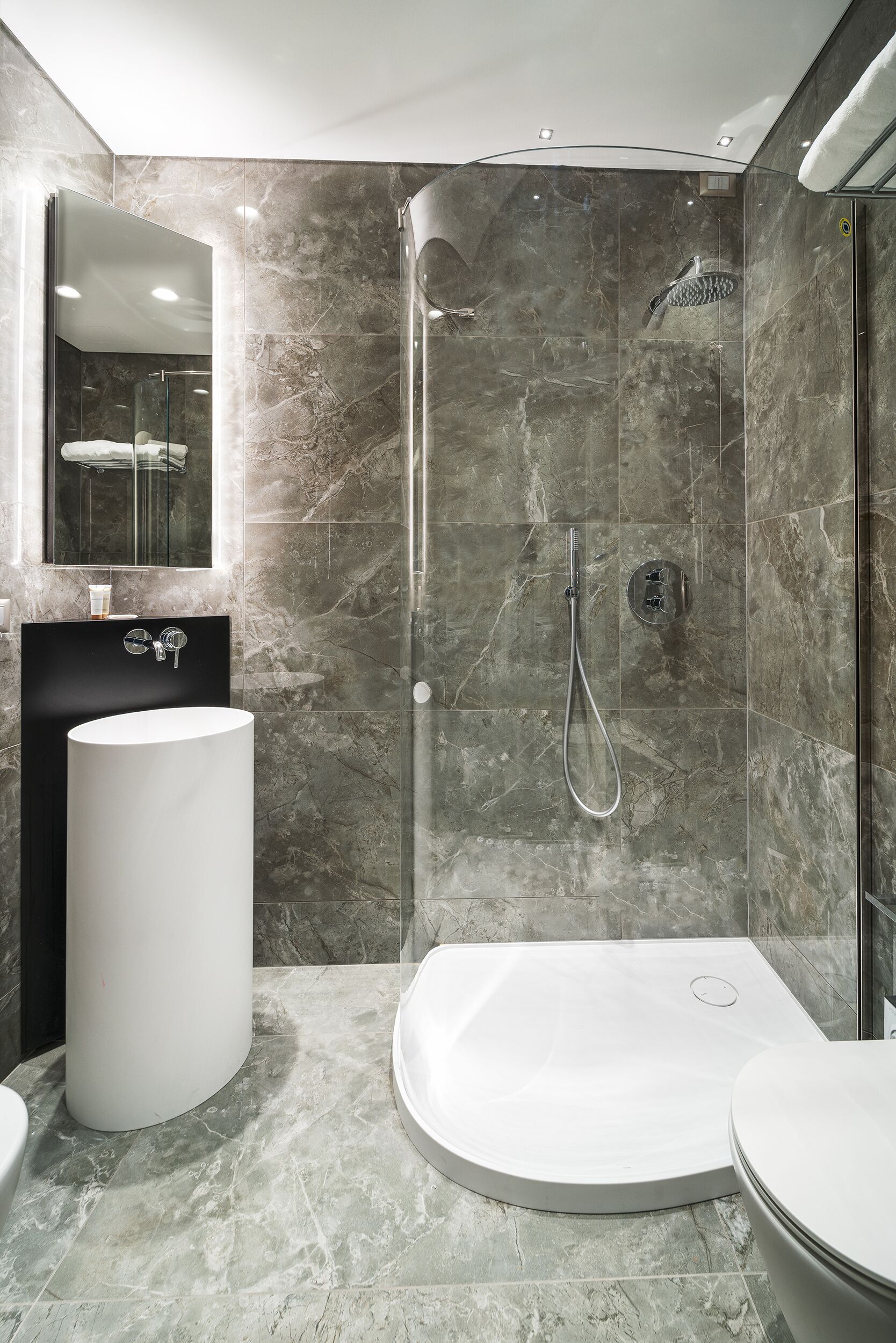 A modern bathroom with a glass-enclosed shower, a standalone sink, and a freestanding bathtub.