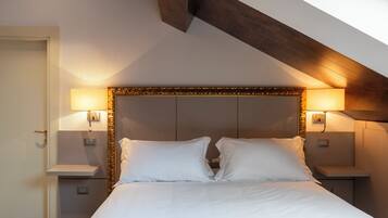 Una habitación de hotel con una cama, dos mesitas de noche y lámparas fijadas a la pared.