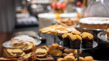 A buffet with various desserts including cakes, muffins, and pastries.