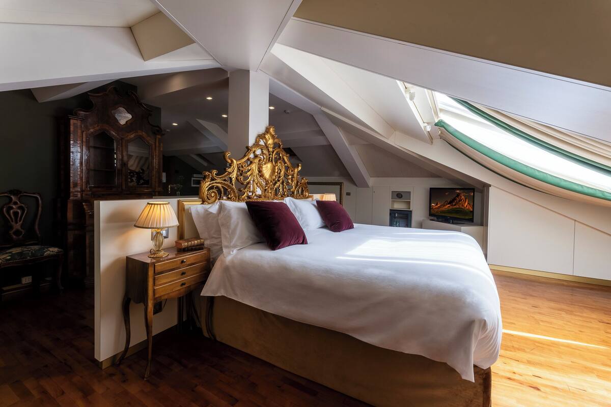 Un dormitorio con una cama grande, una mesita de noche de madera, un aparador y un cabecero decorativo.