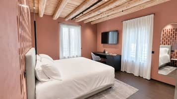 Ett modernt hotellrum med ett träpanelat tak, en stor säng, ett skrivbord, en tv och en spegel.