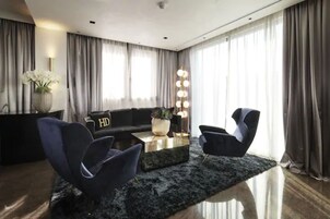 Una sala de estar moderna con un sofá, dos sillones, una mesita de centro y una planta decorativa.
