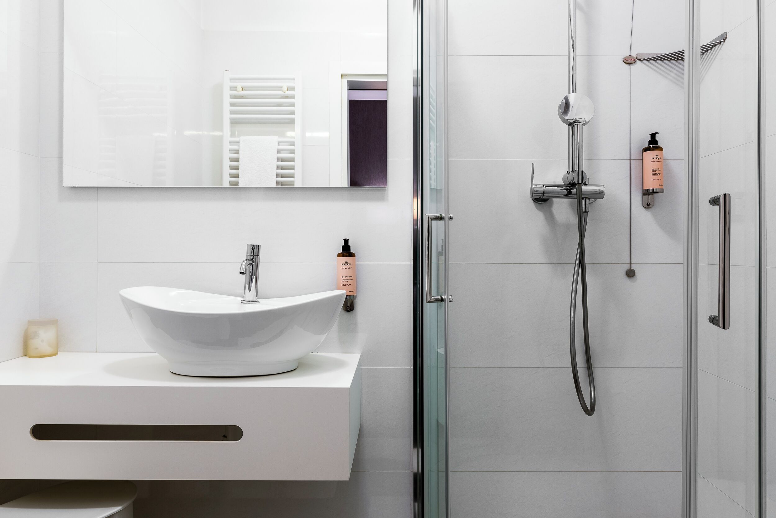 Un baño moderno con un lavabo blanco, un espejo grande y un box de ducha de vidrio.