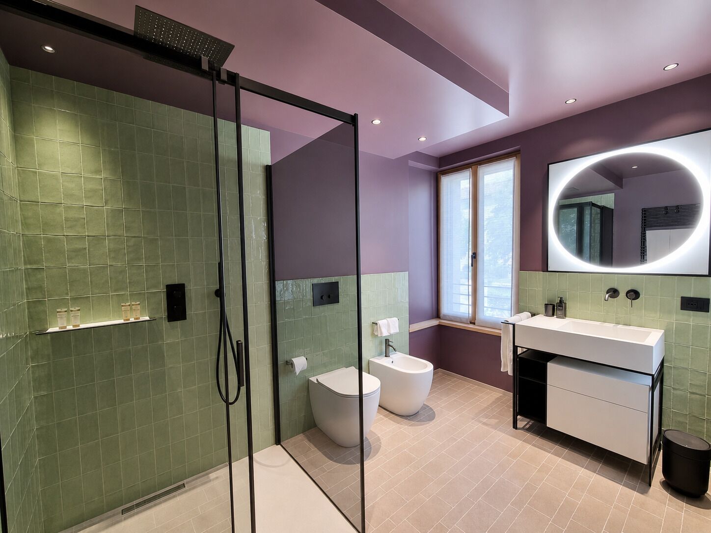 Un baño moderno con cabina de ducha de vidrio, inodoro blanco, bidé, lavabo con espejo y ventana.