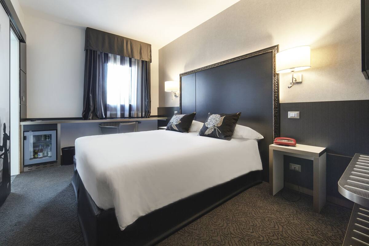 Una habitación de hotel con una cama grande, un escritorio, un refrigerador y un televisor.