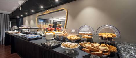 A buffet with various pastries and desserts, a large mirror, and a modern interior design.