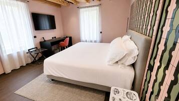 A bedroom with a bed, desk, chair, TV, and patterned wall.