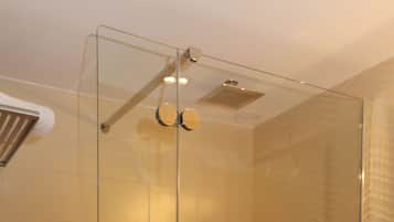 Une salle de bain moderne avec une douche à l’italienne en verre, un lavabo blanc et un sol carrelé de couleur rouge.