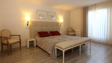 A hotel room with a large bed, two bedside tables, a chair, and a bench.