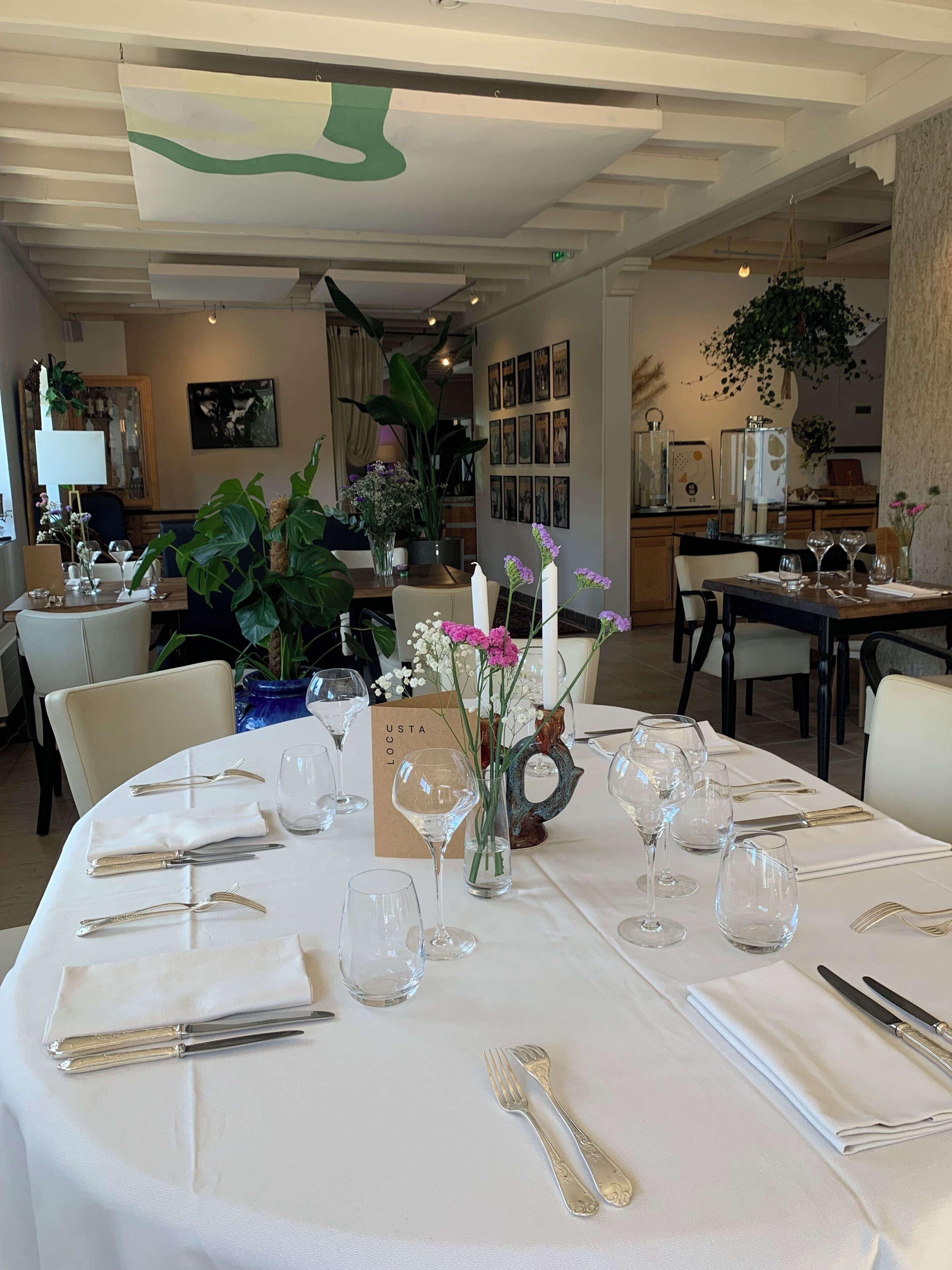 A dining area with tables set for a meal, featuring a white tablecloth, glassware, and cutlery.