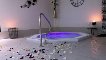 A room with a jacuzzi, a clock on the wall, and scattered flower petals on the floor.