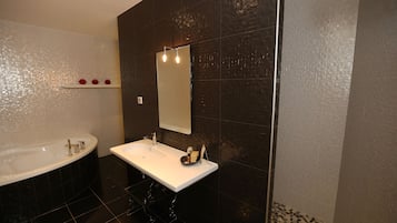 A modern bathroom with a white bathtub, a sink, and a large mirror.