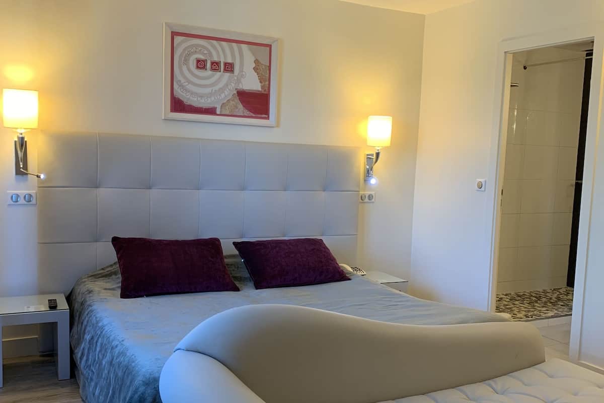 Une chambre à coucher avec un grand lit, deux tables de chevet, une tête de lit et une œuvre d’art accrochée au mur.