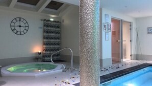 Zona de spa con un jacuzzi, un reloj de pared y cabina de ducha.