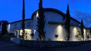 Una casa moderna de dos pisos con techo curvo, base de piedra y entrada bien iluminada.