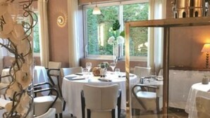 Un restaurante con mesas redondas, manteles blancos y una vela sobre la mesa.