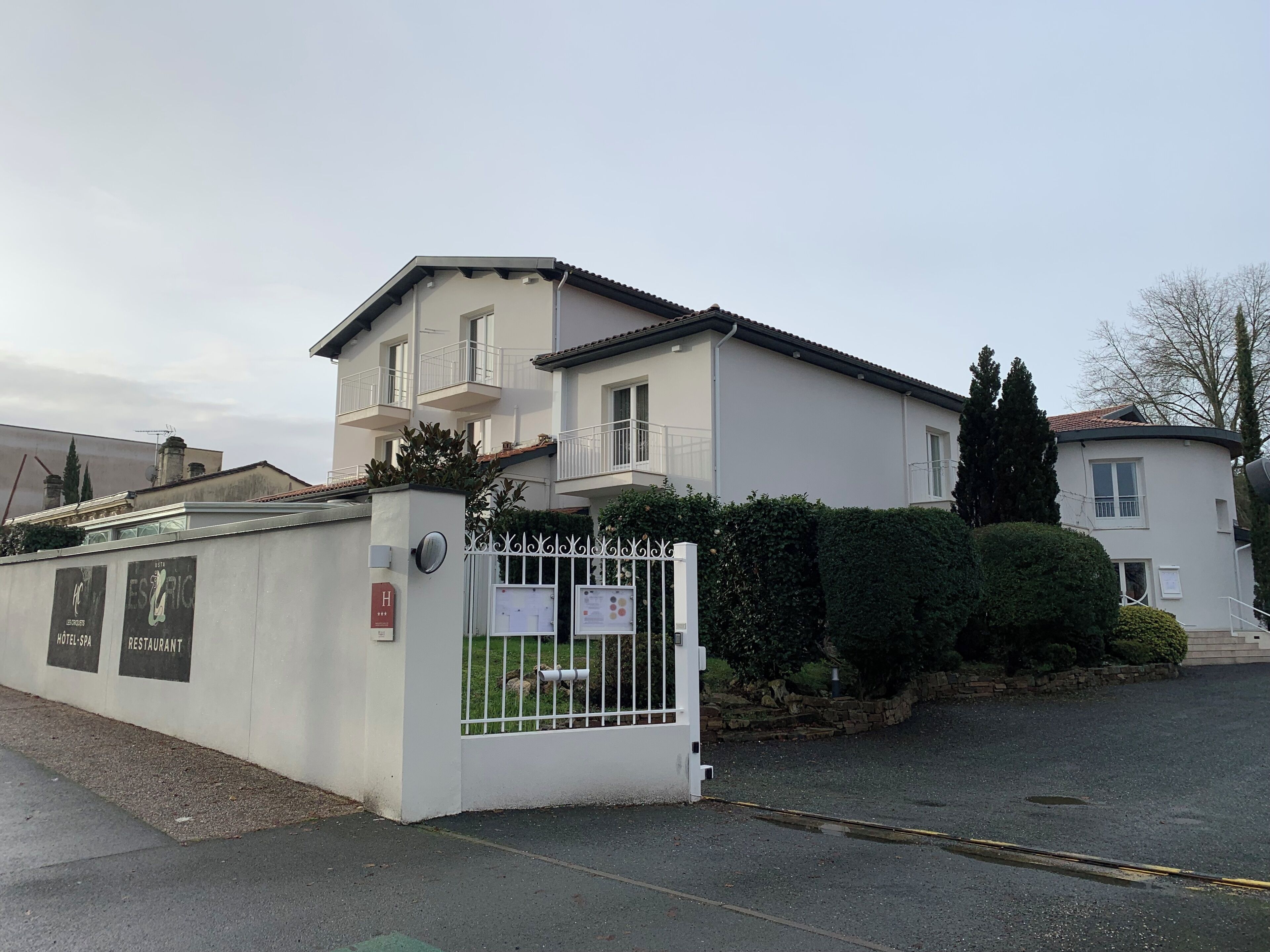 Un edificio a due piani con ingresso recintato, un balcone e un cartello che indica un hotel e un ristorante.