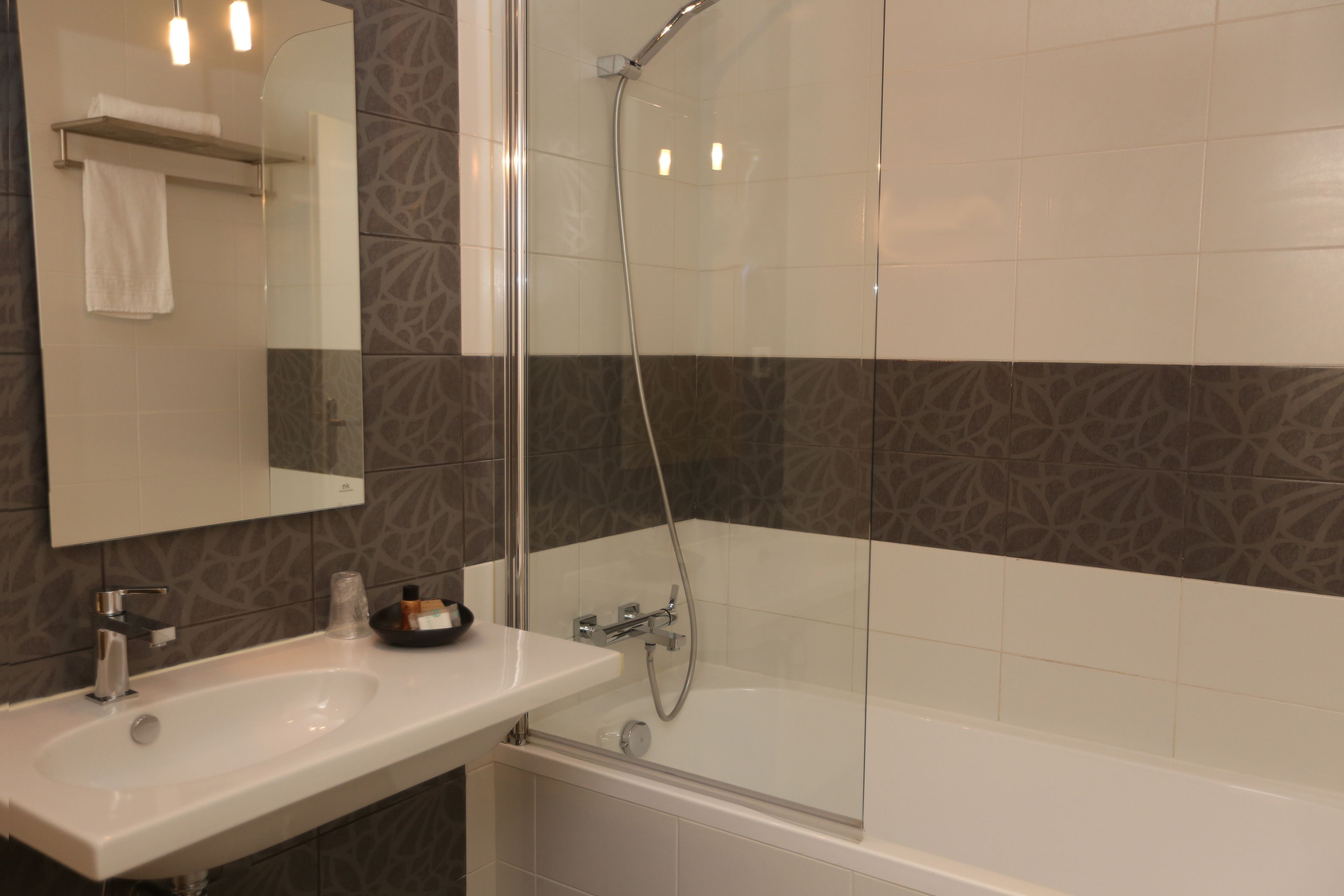 Une salle de bain moderne avec une douche à parois de verre, un lavabo blanc et un grand miroir.