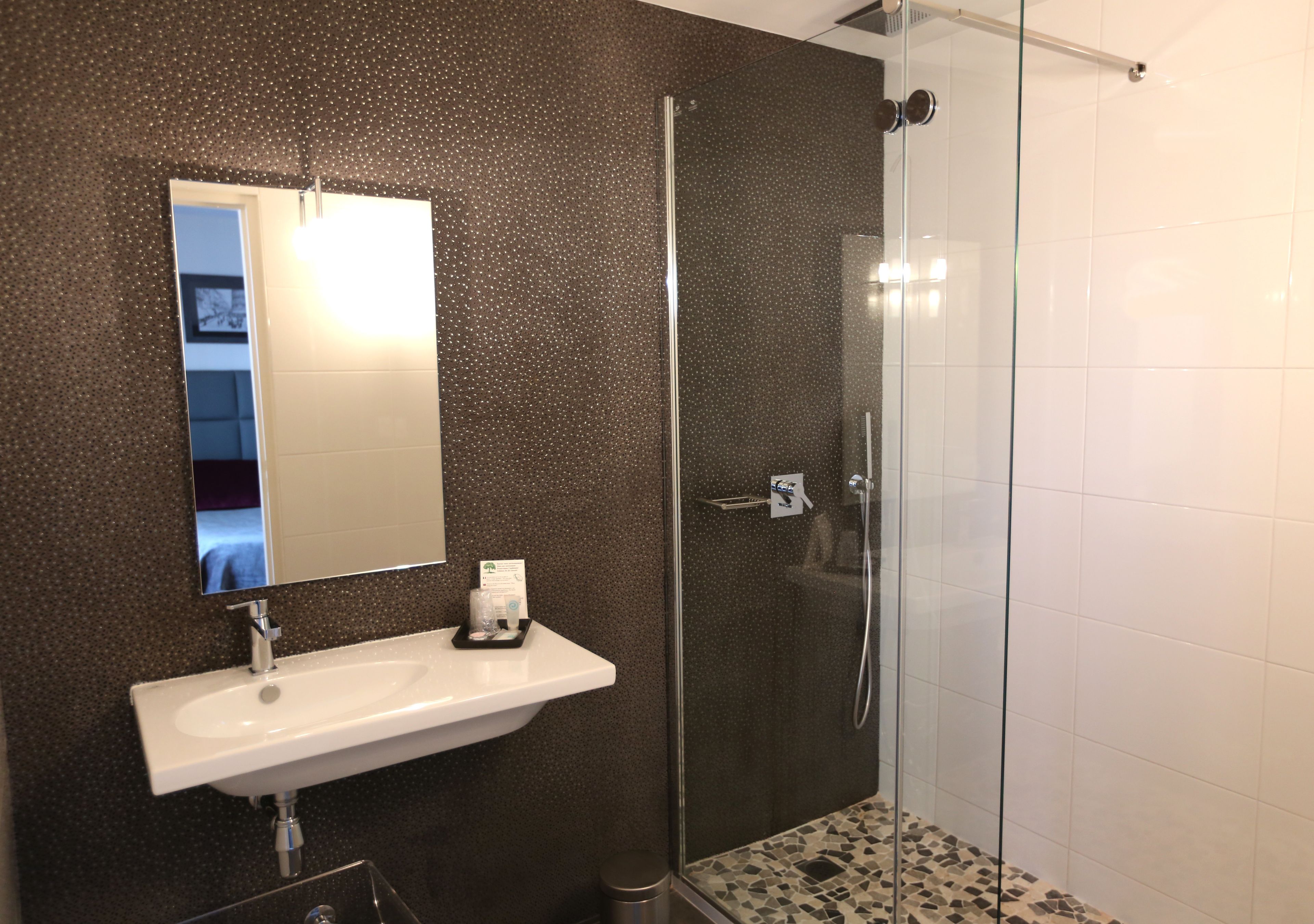 Une salle de bain avec un lavabo blanc, un miroir et une douche à parois de verre.