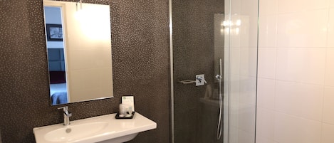 A bathroom with a white sink, a mirror, and a glass-enclosed shower.
