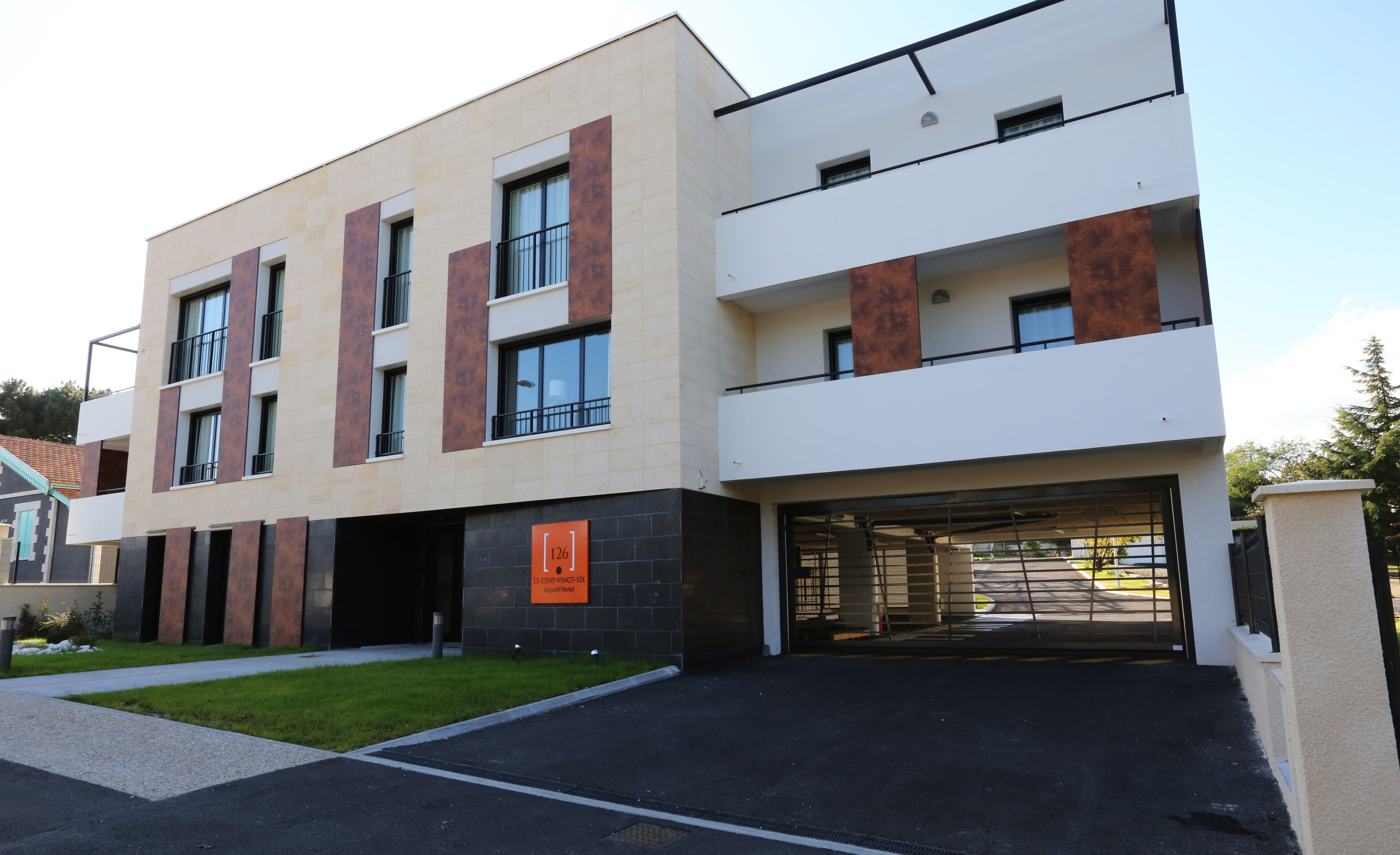 A modern hotel with a flat roof, large windows, and a parking garage.