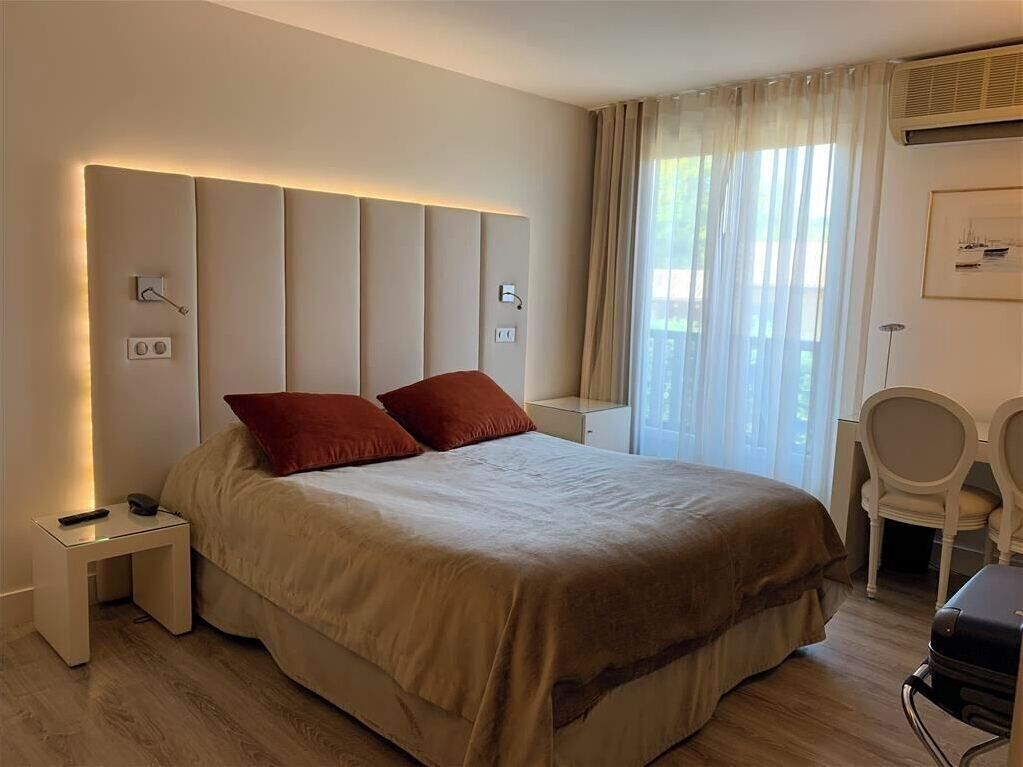 Een hotelkamer met een groot bed, nachtkastjes, een bureau en een stoel.