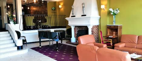 Amplia sala de estar con un piano de cola, sofás de cuero, chimenea y una escalera que conduce a un balcón.